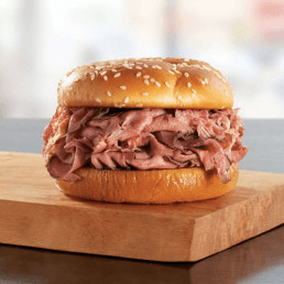 A roast beef sandwich from Arby's served on a wooden cutting board.