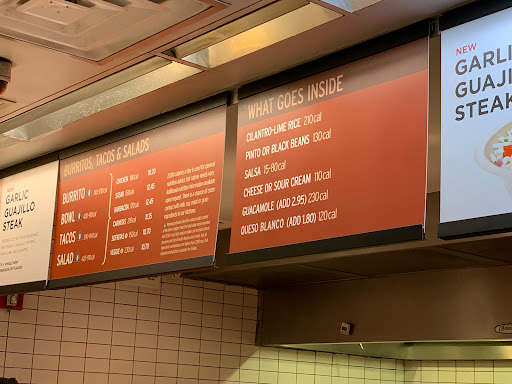 A chipotle menu board with prices for different items in a restaurant.