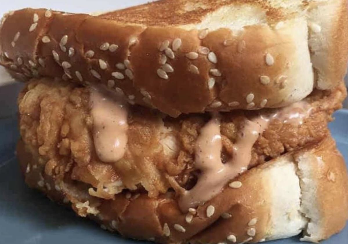 A grilled chicken sandwich from Raising Cane's secret menu is on a plate.