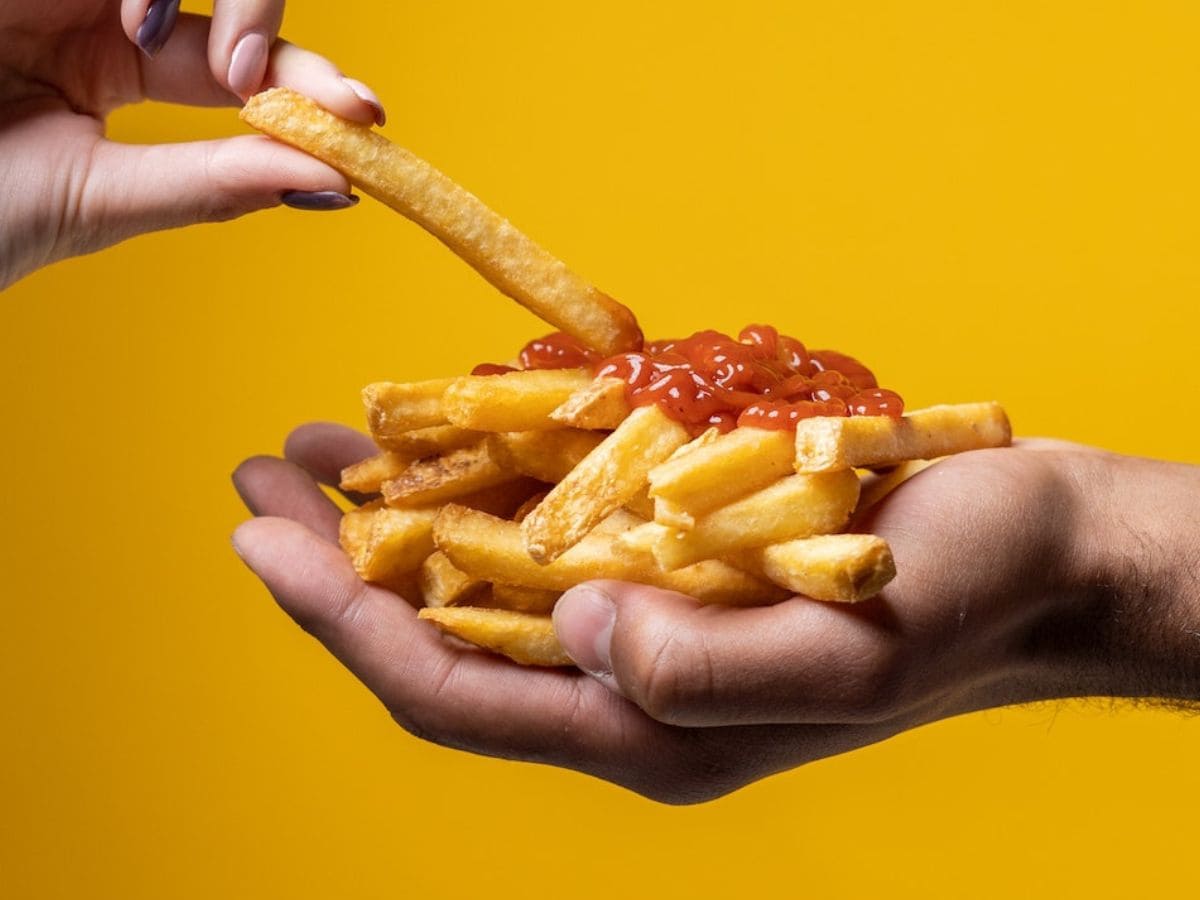 Cheap and fast food: French fries with ketchup on a yellow background.