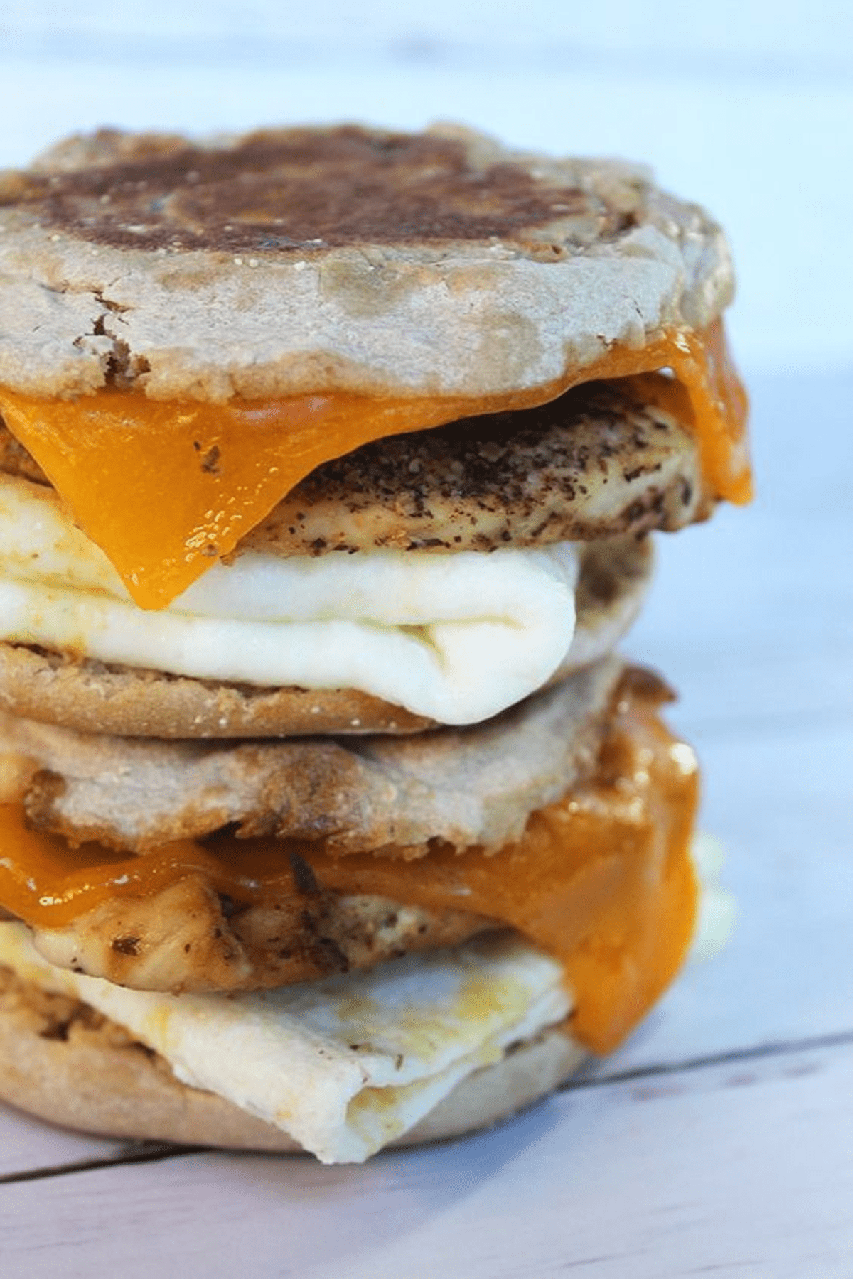 A stack of pancakes with eggs and cheese on top.