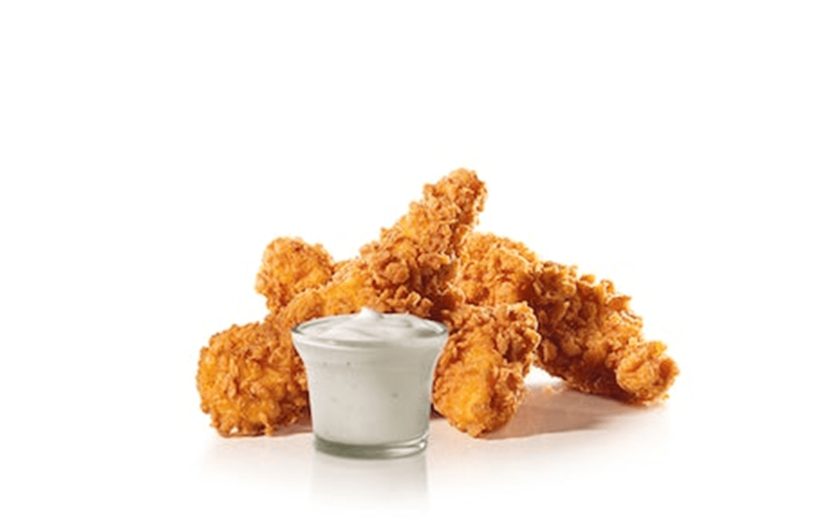 Chicken nuggets and a glass of sour cream on a white background.