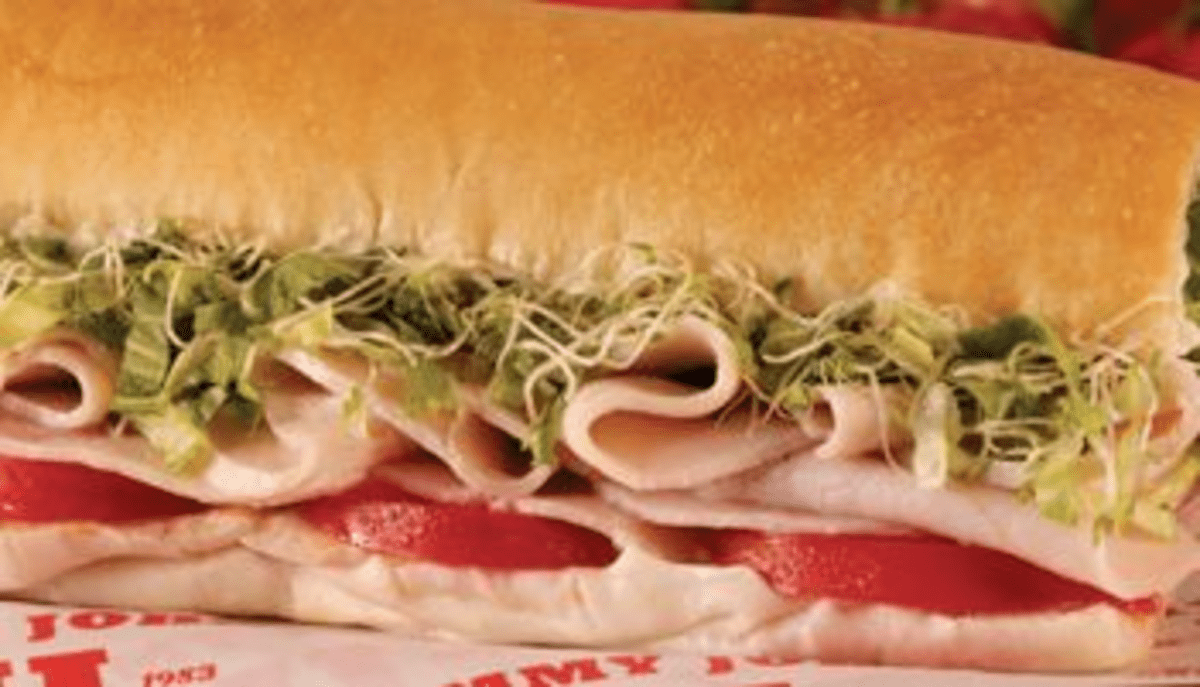 A ham and cheese sub with tomatoes and lettuce.