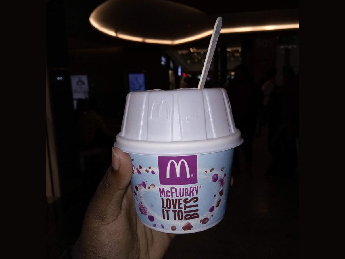 A person holding up a McDonald's cup with a straw, wondering how much is a McFlurry.