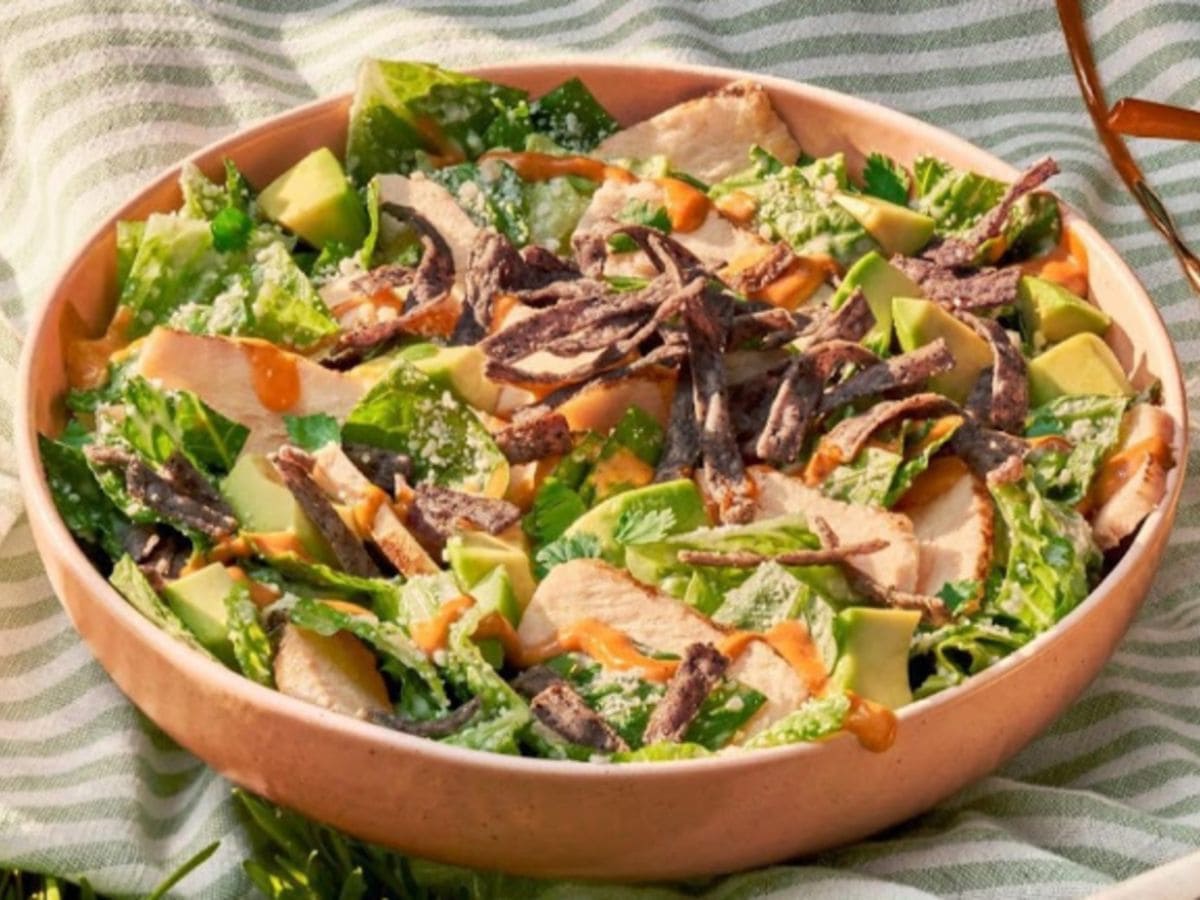 A protein-packed salad bowl with avocado, chicken, and bacon.