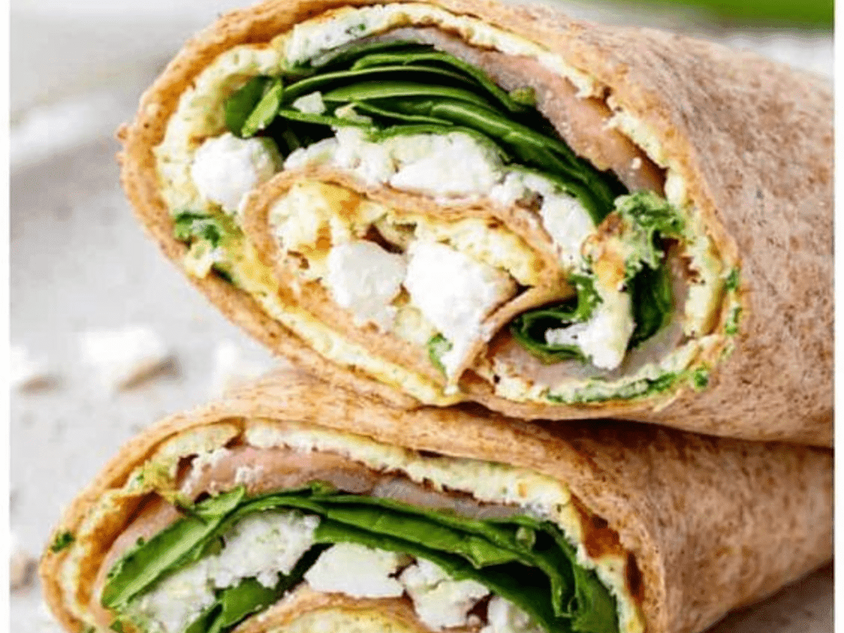 A wrap with spinach and feta cheese on a plate.