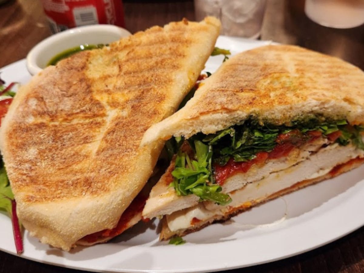 A fast food sandwich with grilled chicken and fresh vegetables on a plate.