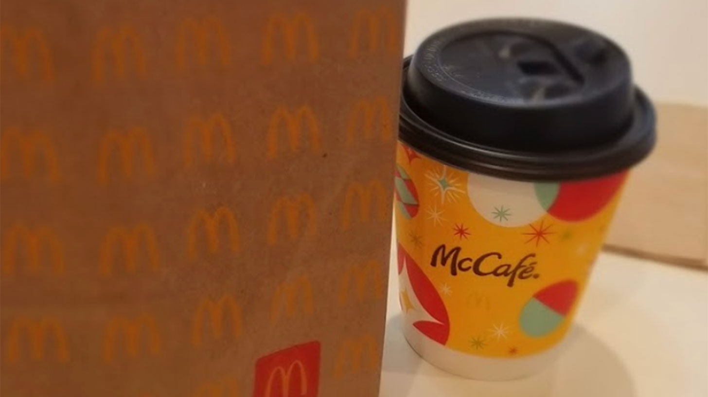 A mcdonald's coffee cup next to a paper bag.