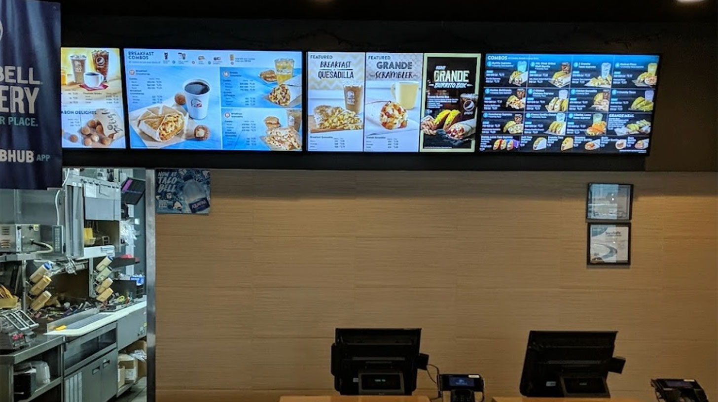 A fast food restaurant with Taco Bell prices on the menu board.