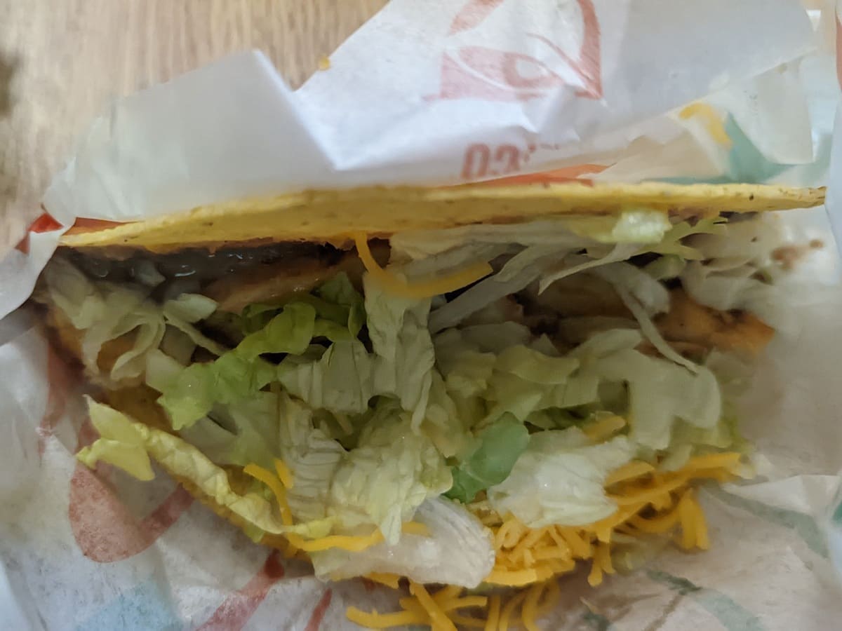 A close up of a taco with lettuce and cheese from Taco Bell.