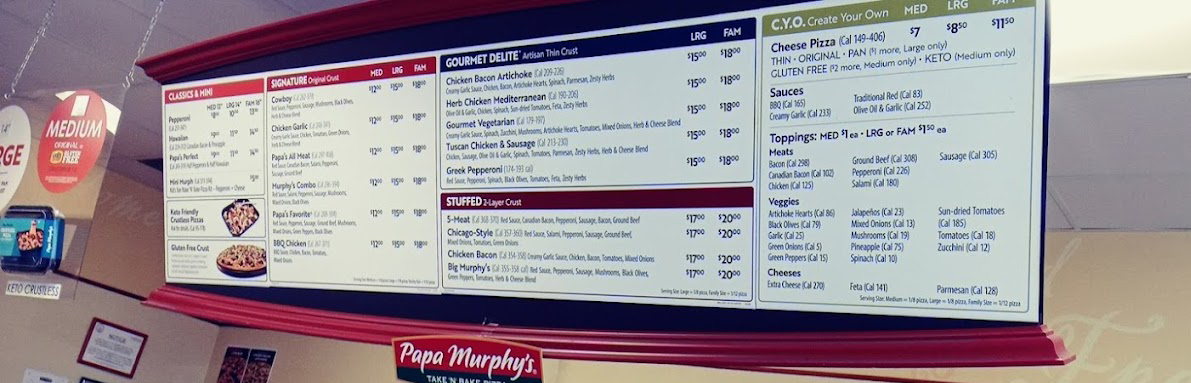 A menu displaying Papa Murphy's prices is displayed on a wall in a restaurant.