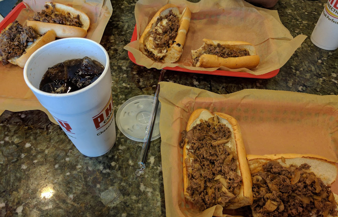 Two hot dogs on a tray with a cup of coffee from Philly Connection.