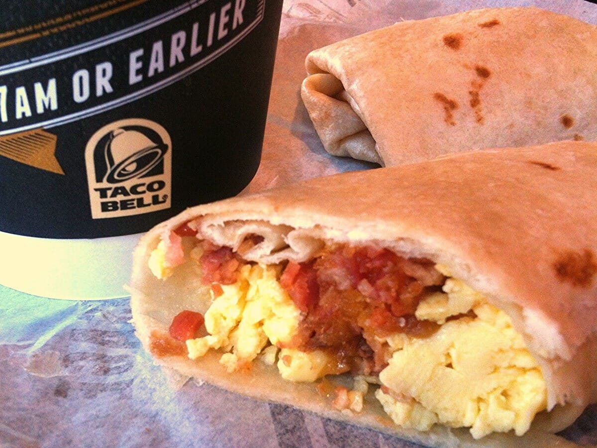 A breakfast burrito from Taco Bell and a cup of coffee.