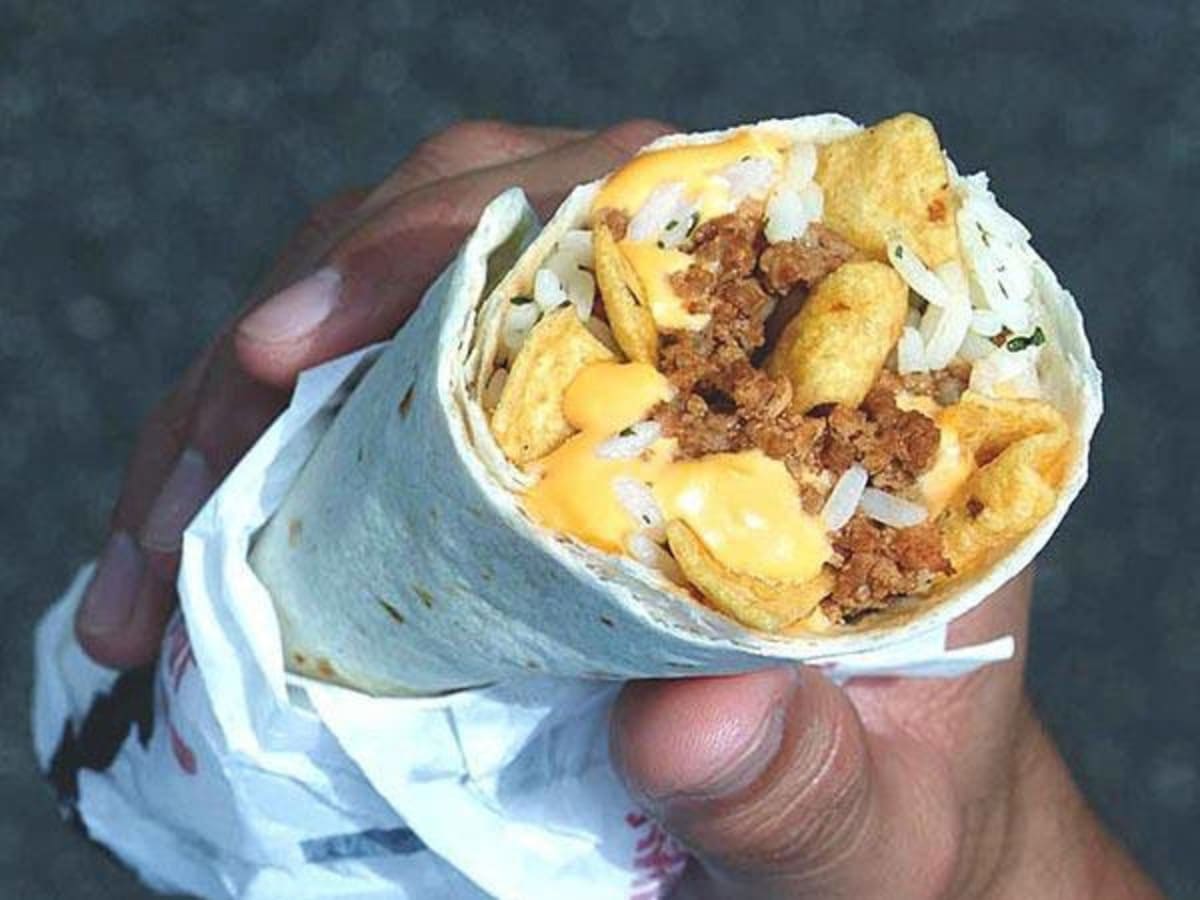 A person holding a gluten free burrito with meat and cheese from Taco Bell.