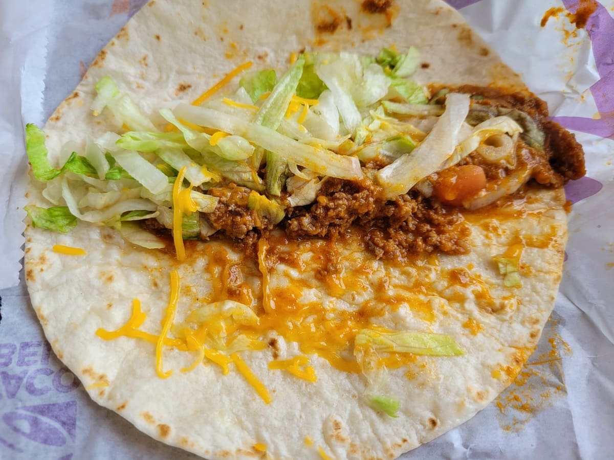 A vegetarian taco is sitting on top of a piece of paper from Taco Bell's menu.