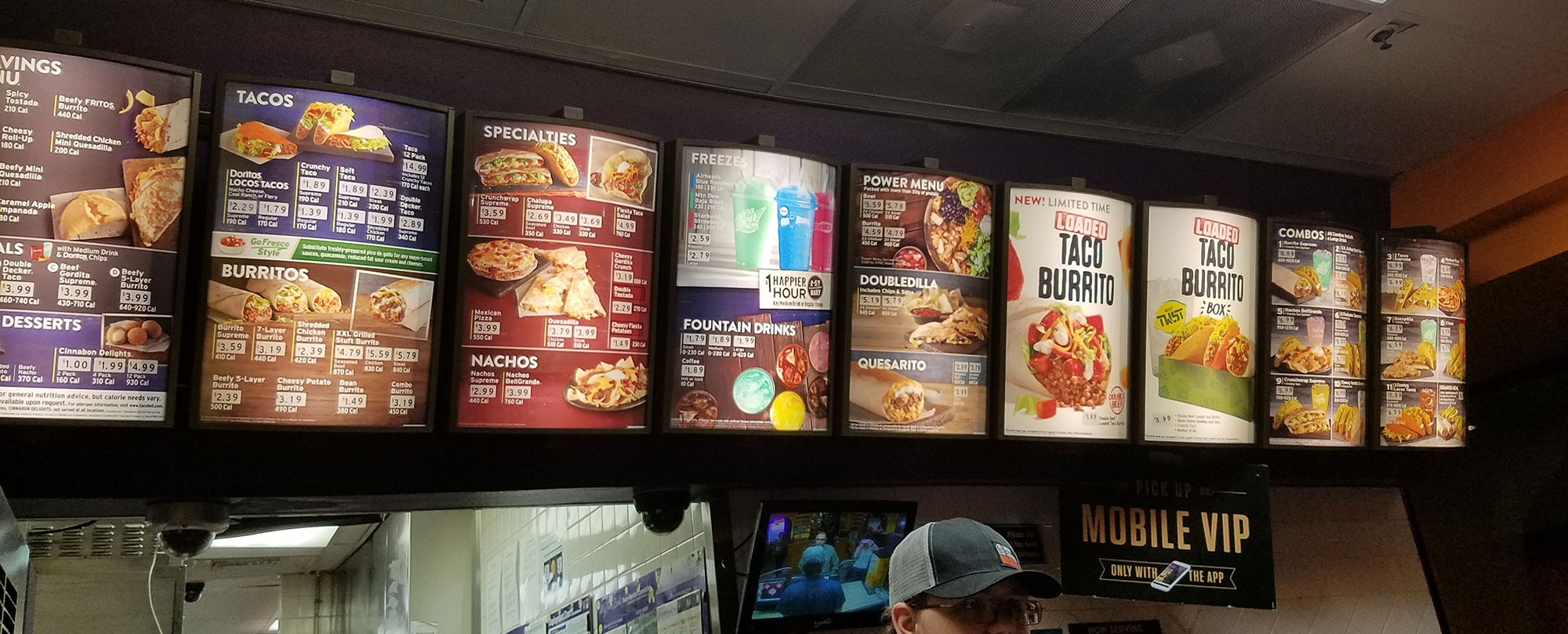A man is standing in front of a fast food menu board.