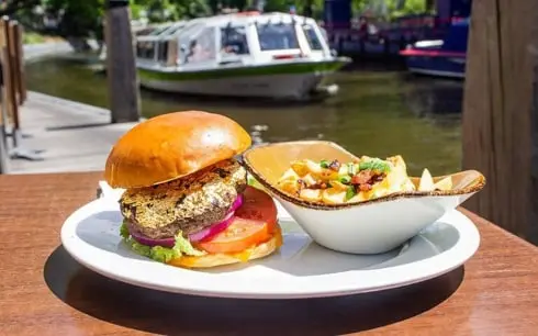 A burger and fries on a plate in front of a boat.