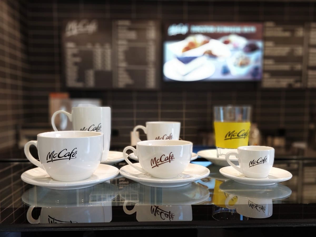 McDonalds Coffee cups and saucers sit on a counter.