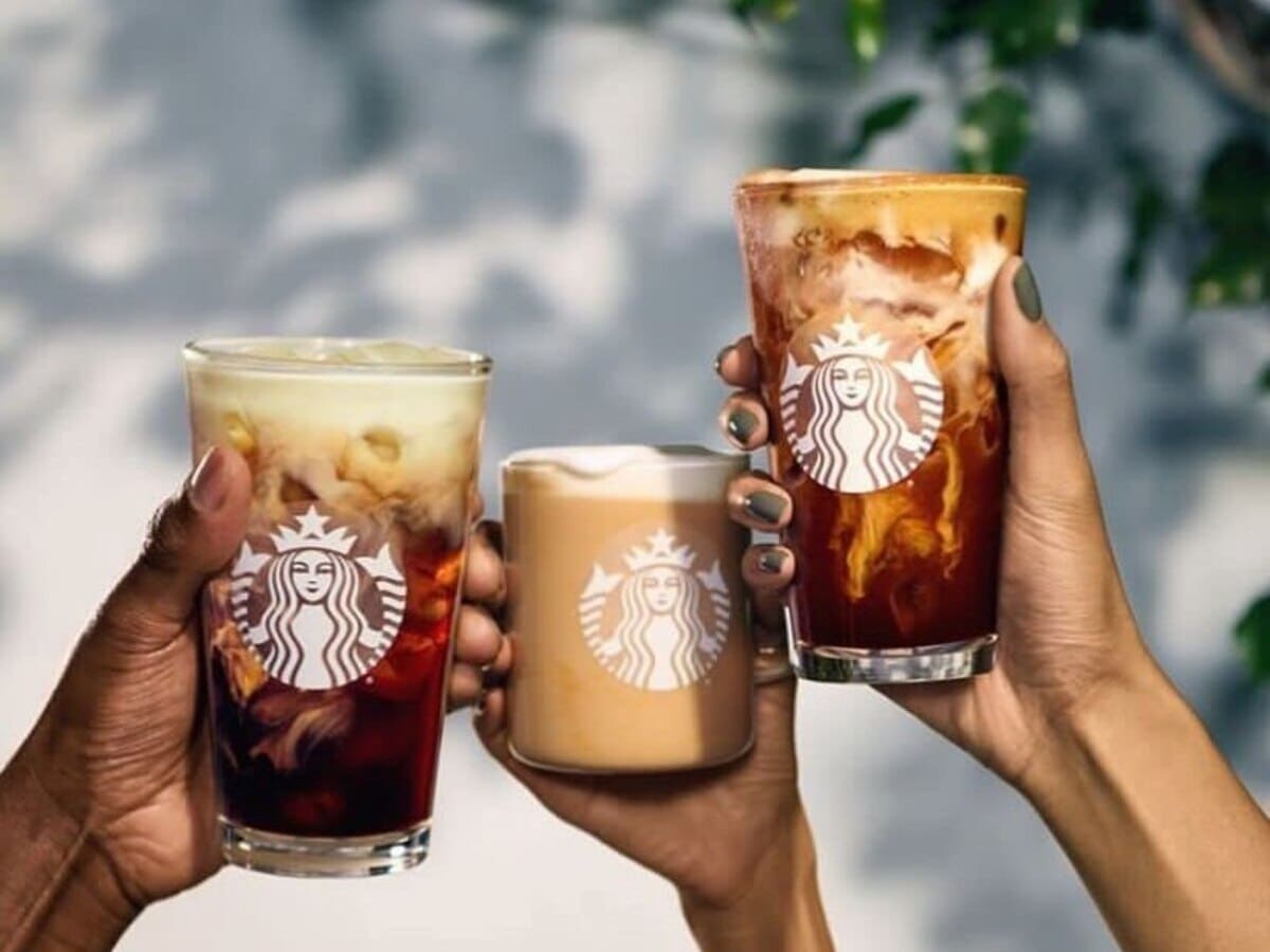 Three people holding up Oleato Starbucks